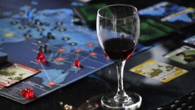 Elegant glass of red wine beside a strategic board game setup on a table.