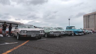 Vintage cars in a parking lot under a cloudy sky, showcasing a classic car meetup.