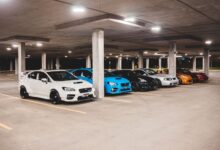 Bright new expensive automobiles placed on parking lot under concrete roof with bright lights