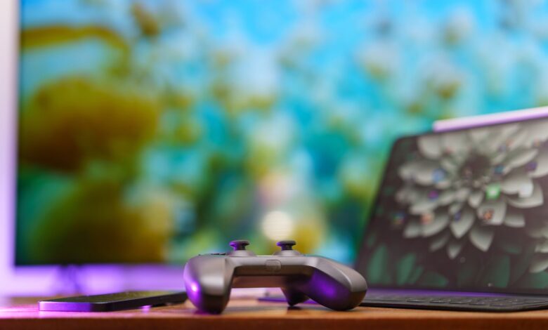 A modern gaming setup featuring a controller, laptop, and vibrant TV screen in a cozy home environment.