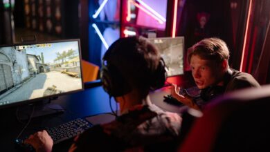 Two gamers engaged in a heated video game session surrounded by neon lights and computer screens.