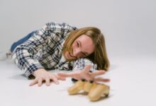 Man in plaid shirt reaching out to grab a gaming controller on a studio floor.