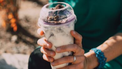Close-up of hands holding a creamy dessert beverage outdoors, showcasing a refreshing treat.