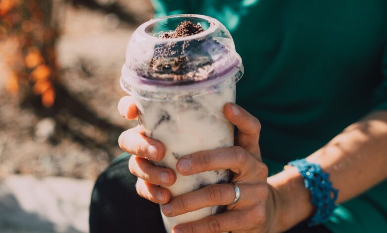 Close-up of hands holding a creamy dessert beverage outdoors, showcasing a refreshing treat.