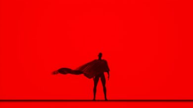 Artistic silhouette of a person with a flowing cape against a vivid red backdrop, creating a dramatic effect.