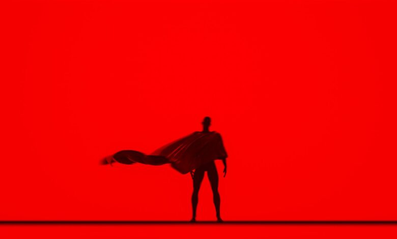 Artistic silhouette of a person with a flowing cape against a vivid red backdrop, creating a dramatic effect.
