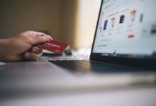 Person holding a credit card while shopping online on a laptop, indicating ecommerce transactions.