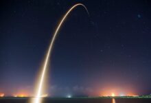 Spectacular long exposure of a rocket launch under a clear, starry night sky showcasing the trail.