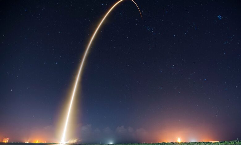 Spectacular long exposure of a rocket launch under a clear, starry night sky showcasing the trail.