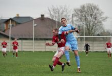 Players fiercely competing in a local football match on an outdoor grassy field.