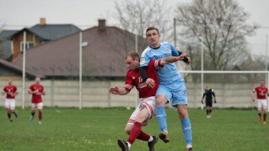 Players fiercely competing in a local football match on an outdoor grassy field.