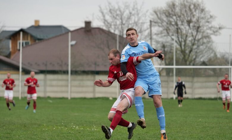 Players fiercely competing in a local football match on an outdoor grassy field.