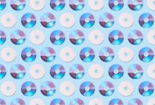 Colorful CDs arranged in a geometric pattern on a light blue background, creating a vibrant visual.