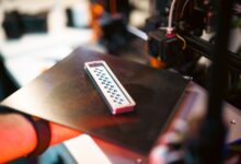 Close-up of a 3D printed part on an industrial printer in a workshop setting.