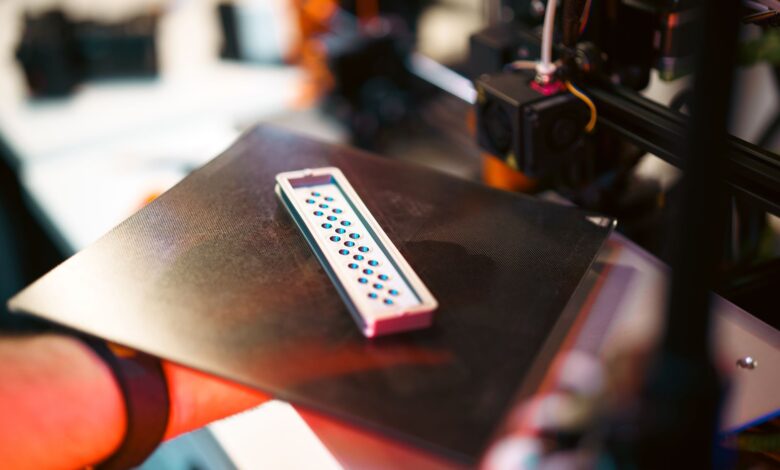 Close-up of a 3D printed part on an industrial printer in a workshop setting.