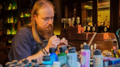 Skilled artisan meticulously painting miniatures in a cozy, cluttered workshop with various vibrant paints.