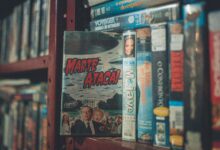 A nostalgic display of vintage VHS tapes with classic movie titles on a wooden shelf indoors.