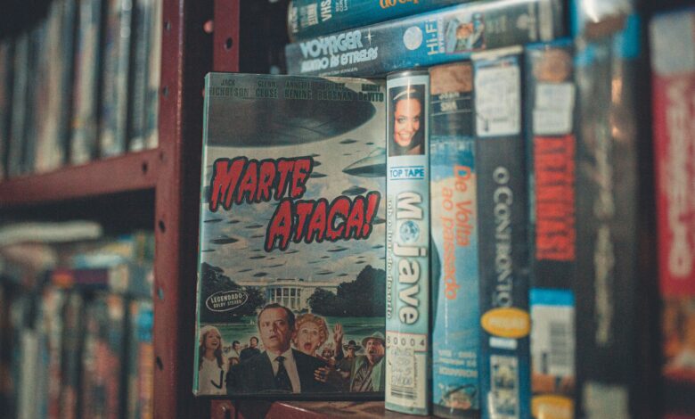 A nostalgic display of vintage VHS tapes with classic movie titles on a wooden shelf indoors.