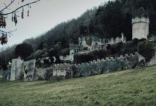 Explore the haunting ruins of the medieval Gwrych Castle set against a lush green hillside in Abergele, Wales.