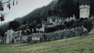 Explore the haunting ruins of the medieval Gwrych Castle set against a lush green hillside in Abergele, Wales.