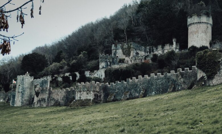 Explore the haunting ruins of the medieval Gwrych Castle set against a lush green hillside in Abergele, Wales.