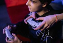 Close-up of teenagers playing video games together using modern game controllers.