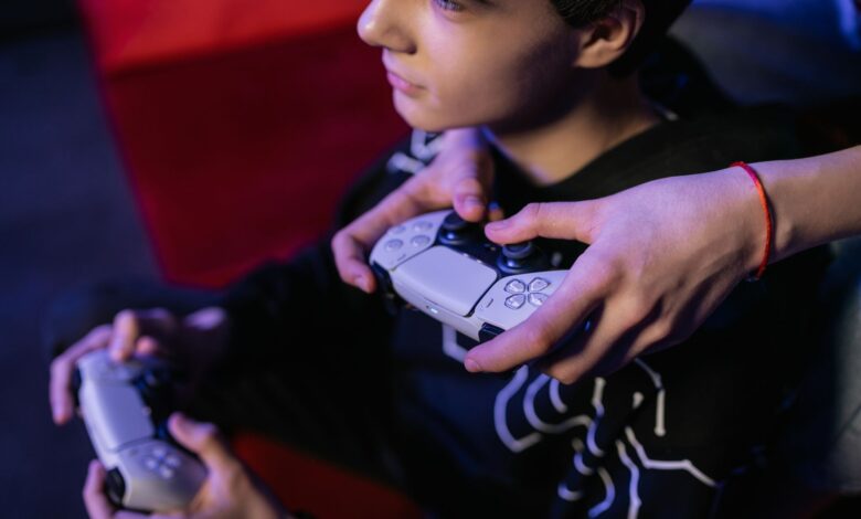 Close-up of teenagers playing video games together using modern game controllers.