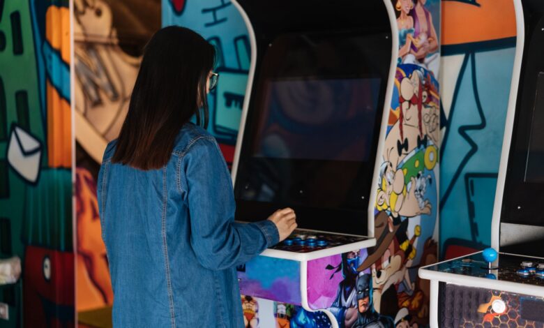 A woman with long hair plays a retro arcade game indoors, enjoying classic gaming fun.