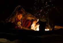 Warm campfire scene with a person in fur clothing enjoying a cozy night outdoors.