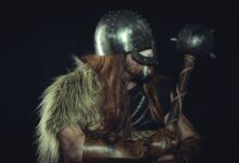 Viking warrior in medieval armor holding a mace, with fur cloak and metal helmet.