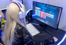 Young woman gaming at a PC high-tech setup, wearing headphones.