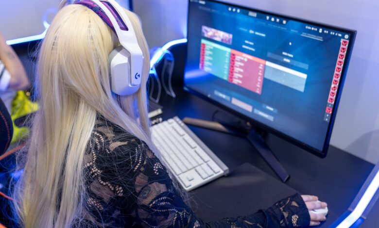 Young woman gaming at a PC high-tech setup, wearing headphones.