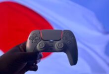 A PlayStation 5 DualSense controller is held up against a backdrop of the Japanese flag.
