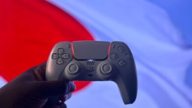 A PlayStation 5 DualSense controller is held up against a backdrop of the Japanese flag.