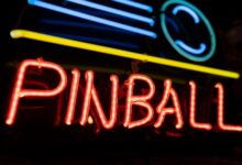 A colorful neon sign illuminating the word 'PINBALL' against a dark background, capturing a retro nightlife vibe.
