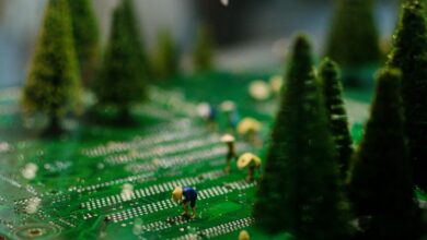 Creative scene of miniature figures farming on a circuit board with artificial trees.