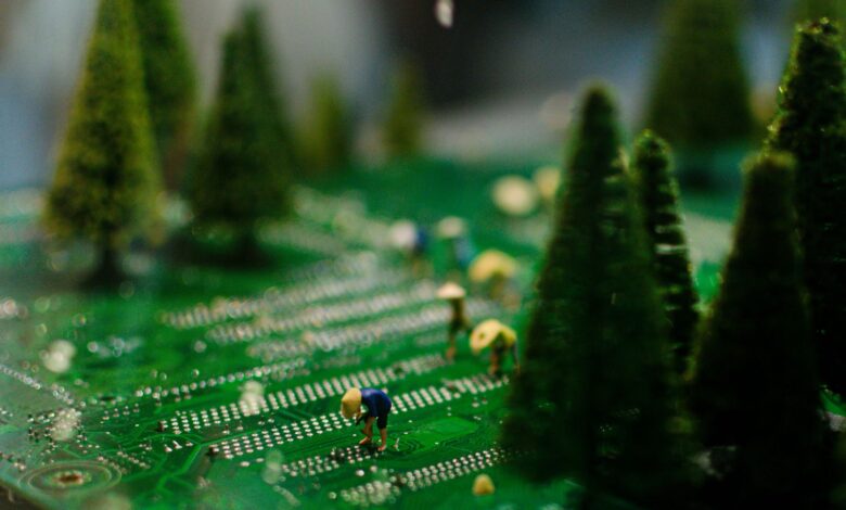 Creative scene of miniature figures farming on a circuit board with artificial trees.