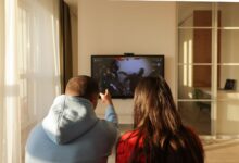 A couple enjoys playing video games in a cozy home setting, bonding over shared hobbies.