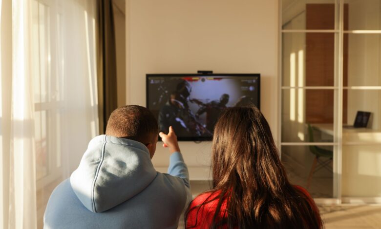 A couple enjoys playing video games in a cozy home setting, bonding over shared hobbies.