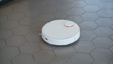 A sleek, white robotic vacuum cleaner operating on a hexagonal tiled floor.
