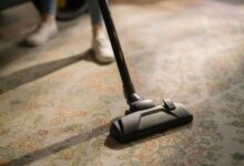 Close-up of a vacuum cleaner on a patterned carpet in a sunlit room, capturing a moment of household cleaning.
