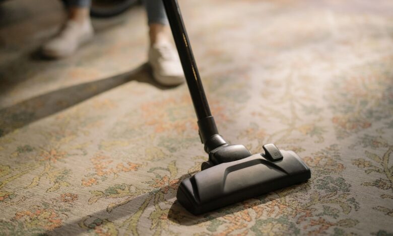 Close-up of a vacuum cleaner on a patterned carpet in a sunlit room, capturing a moment of household cleaning.