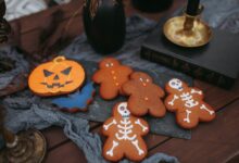Halloween-themed cookies featuring skeletons and pumpkins on a spooky setup.