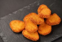 Delicious golden chicken nuggets stacked on a slate plate, ready to serve.