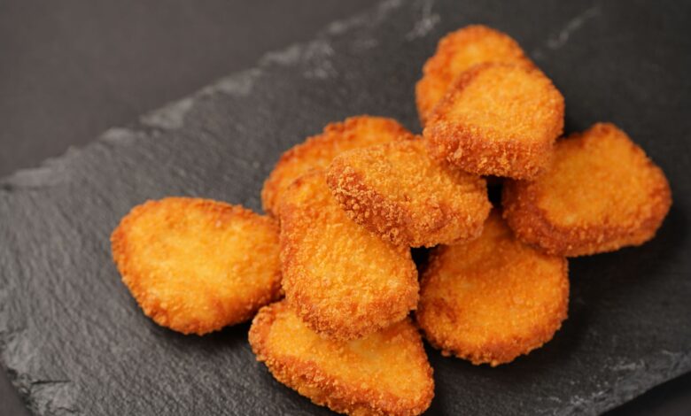 Delicious golden chicken nuggets stacked on a slate plate, ready to serve.