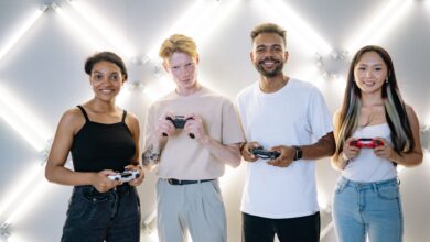 A diverse group of young adults smiling and holding game controllers indoors.