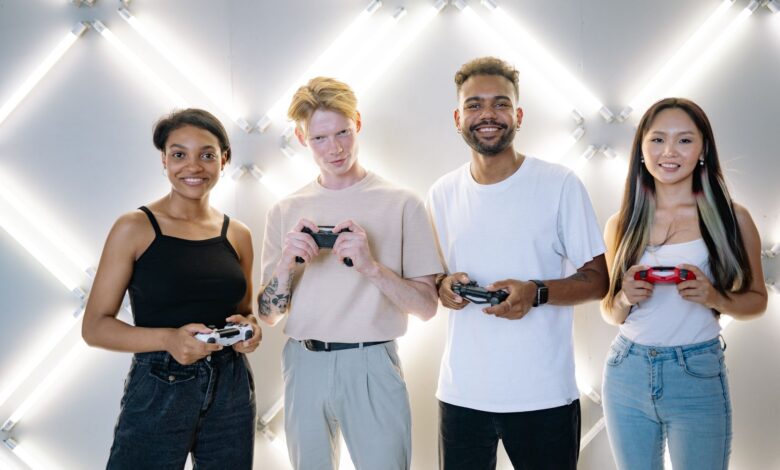 A diverse group of young adults smiling and holding game controllers indoors.