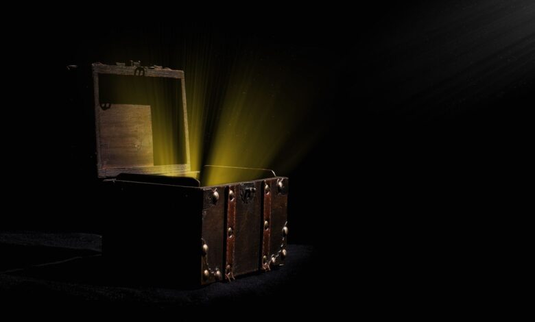 Open wooden chest emitting a mysterious glowing light in a dark room.