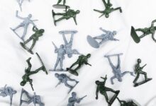 Green and grey plastic toy soldiers arranged randomly on a white background.