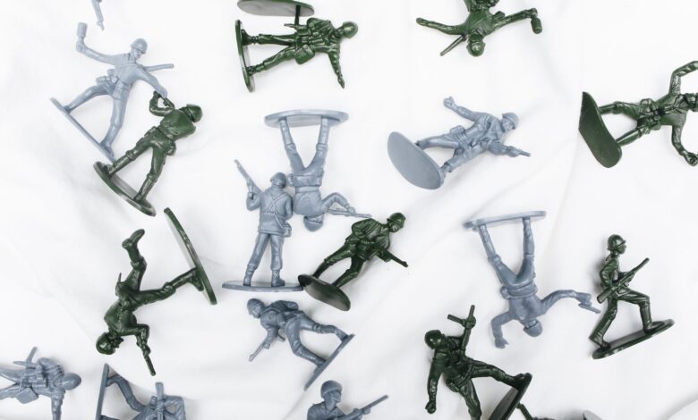 Green and grey plastic toy soldiers arranged randomly on a white background.